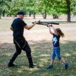 Vater und Sohn kämpfen im Park mit Schaumstoffschwertern